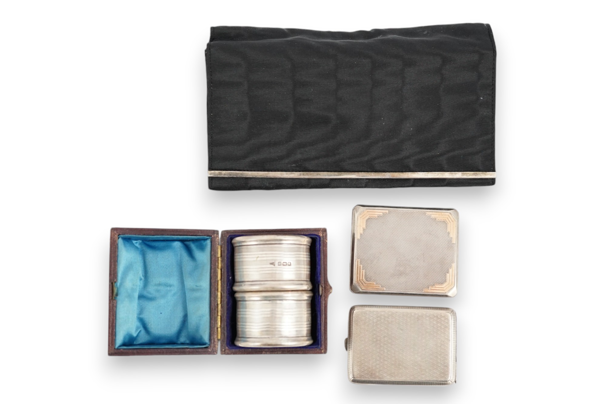 An Art Deco engine turned silver match sleeve by Asprey & Co, Birmingham, 1933, 6cm, together with one other silver match sleeve, a cased pair of silver napkin rings and a continental silver mounted four piece vanity set